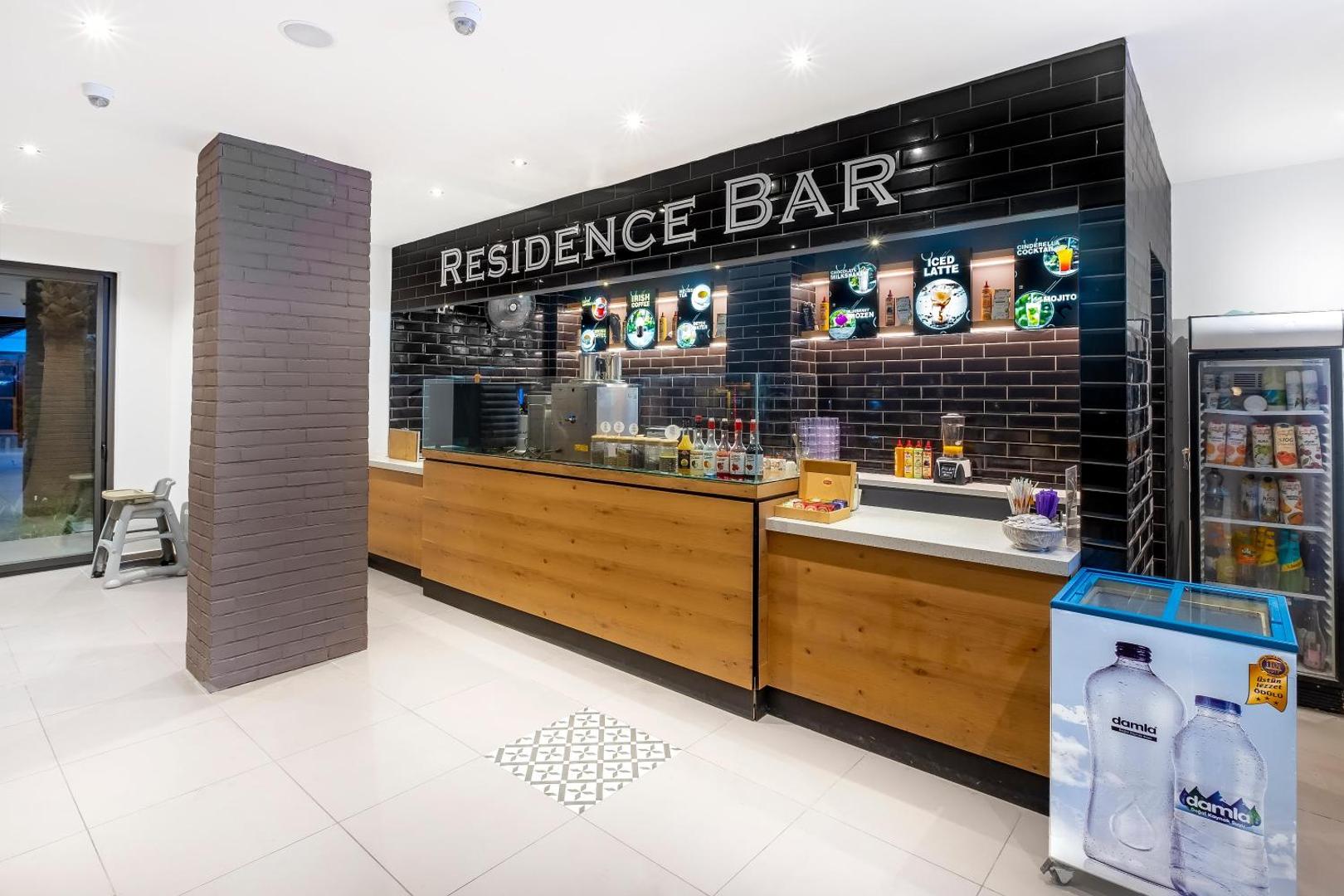 Utopia Resort & Residence Residence Bar ar modernu koka un melnu flīžu apdari, piedāvājot atspirdzinošus dzērienus un kokteiļus