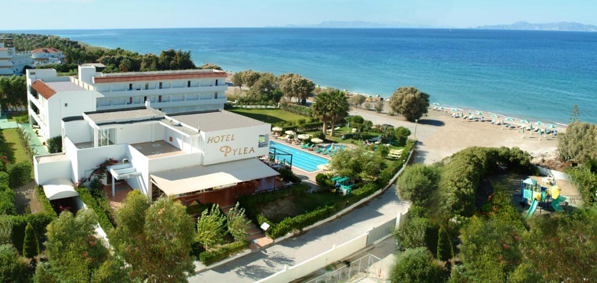 Pylea Beach Hotel panorāmas skats Rodas salā — viesnīcas ēkas, āra baseins un tieša piekļuve smilšu pludmalei pie Egejas jūras