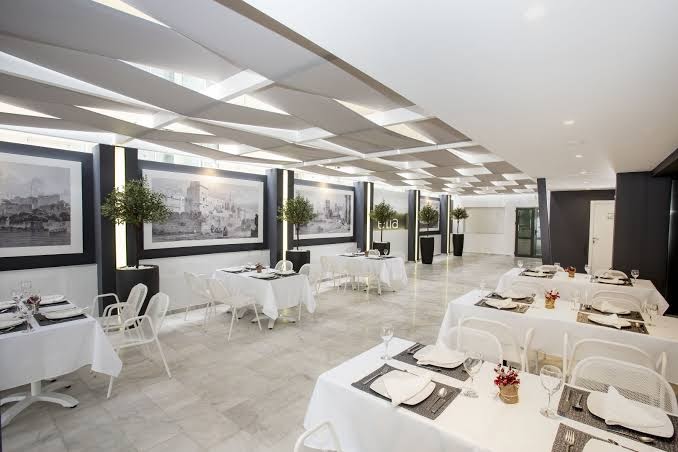 Mercure Rhodes Alexia Hotel & Spa modernais restorāns ar balti klātiem galdiem, dizaina griestiem un mākslas darbiem pie sienām.