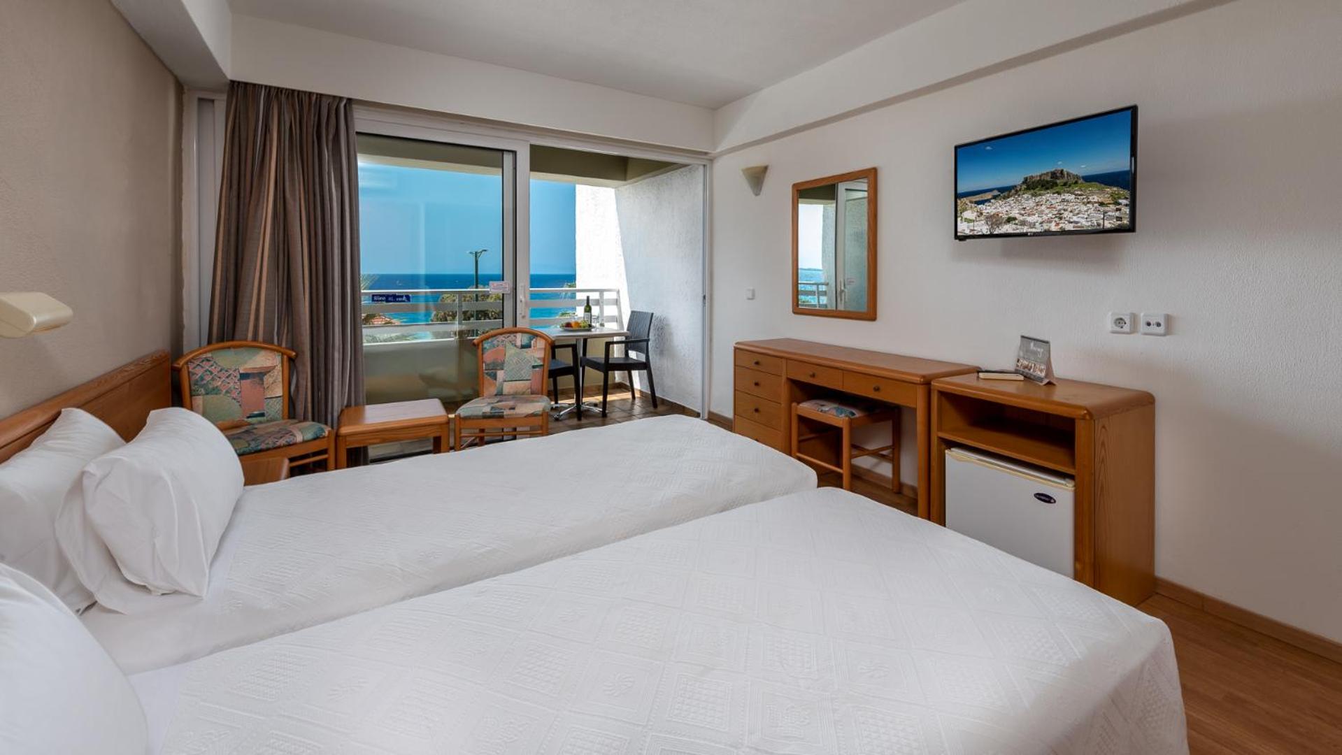 Sirene Beach Hotel numurs Rodas salā ar skatu uz jūru, gaišām mēbelēm, divām gultām un privātu balkonu piekrastē