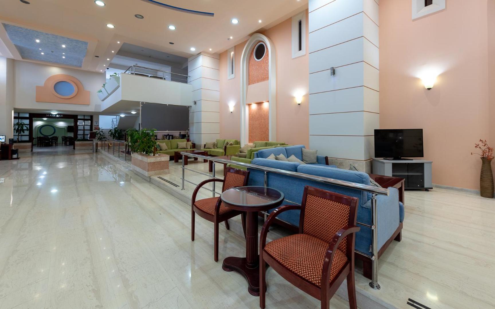 Sirene Beach Hotel lobby zona ar atpūtas dīvāniem, krēsliem un gaišu interjeru — plaša vestibila telpa viesu uzņemšanai