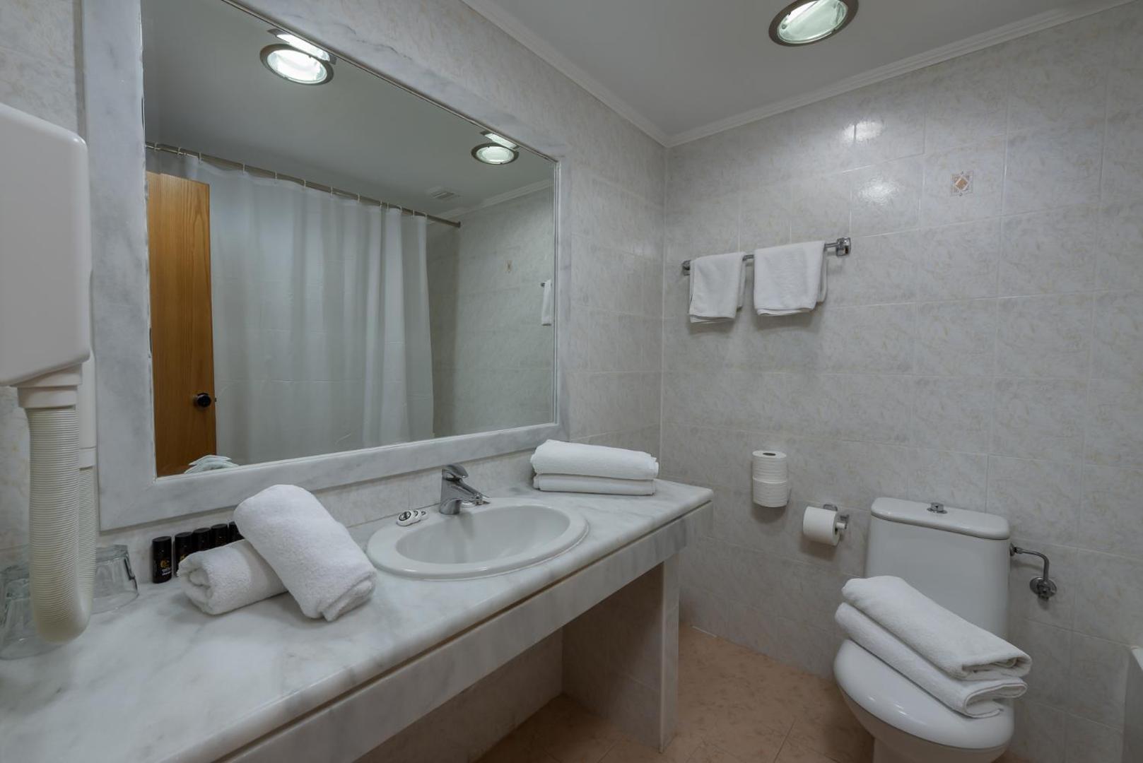 Sirene Beach Hotel numura vannas istaba ar gaišām flīzēm, lielu spoguli, vannu un tīriem dvieļiem