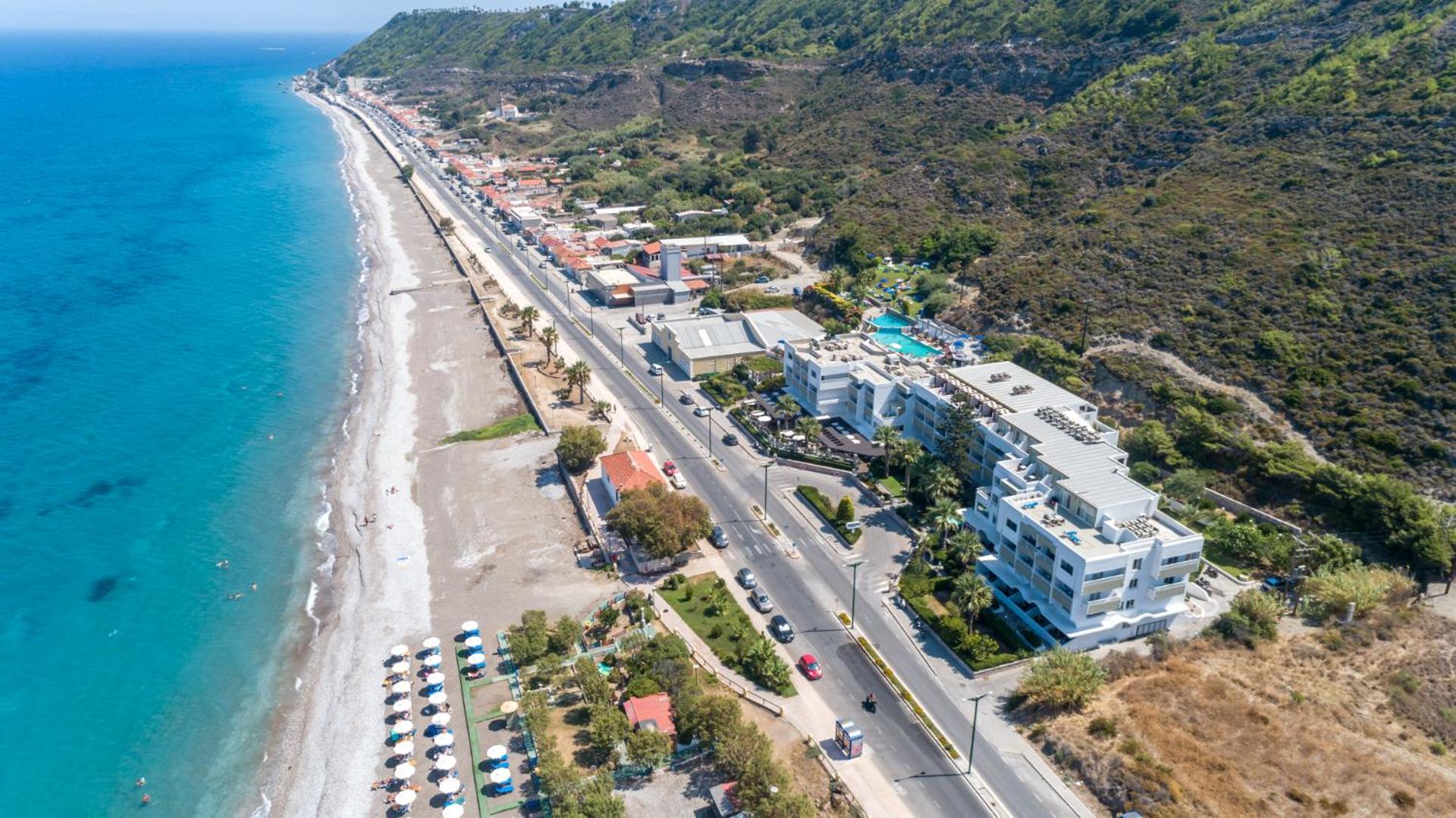 Sirene Beach Hotel Rodas salā skats no putna lidojuma uz piekrasti, oļu pludmali un viesnīcas ēku pie kalna
