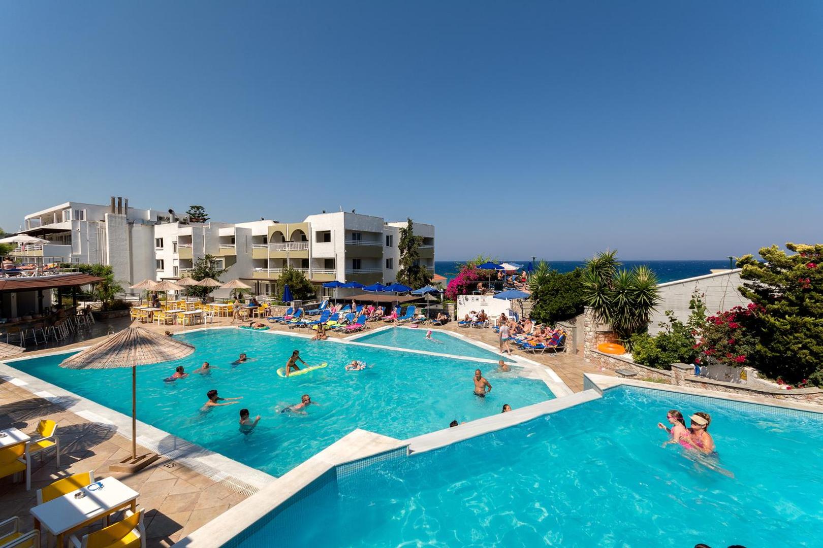 Sirene Beach Hotel daudzlīmeņu baseinu komplekss ar viesnīcas korpusu fonā, atpūtniekiem un saulainu terasi Rodā