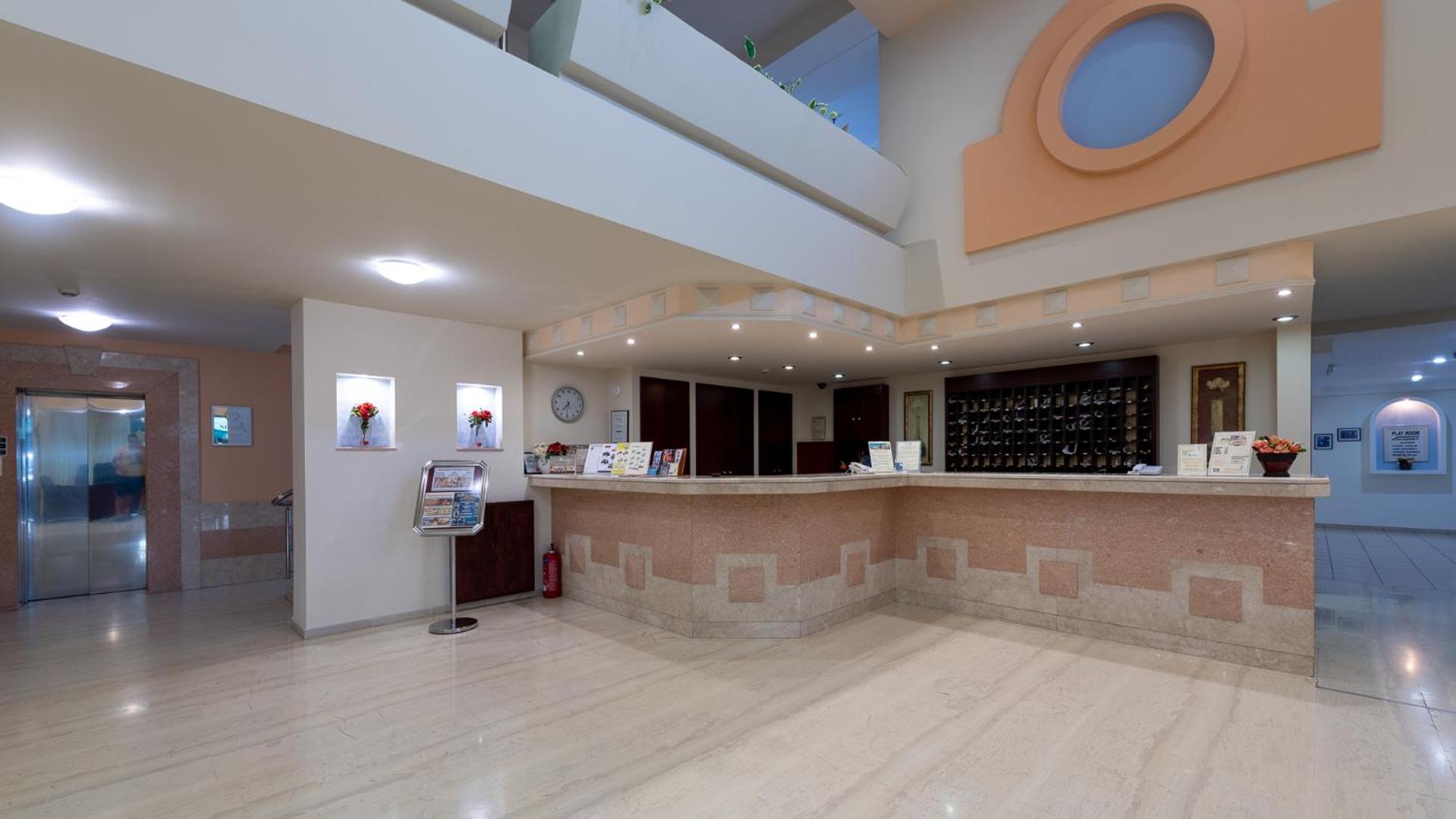 Sirene Beach Hotel gaišā un plašā vestibila zona ar marmora grīdu un recepcijas galdiņu Rodas salā, Grieķijā