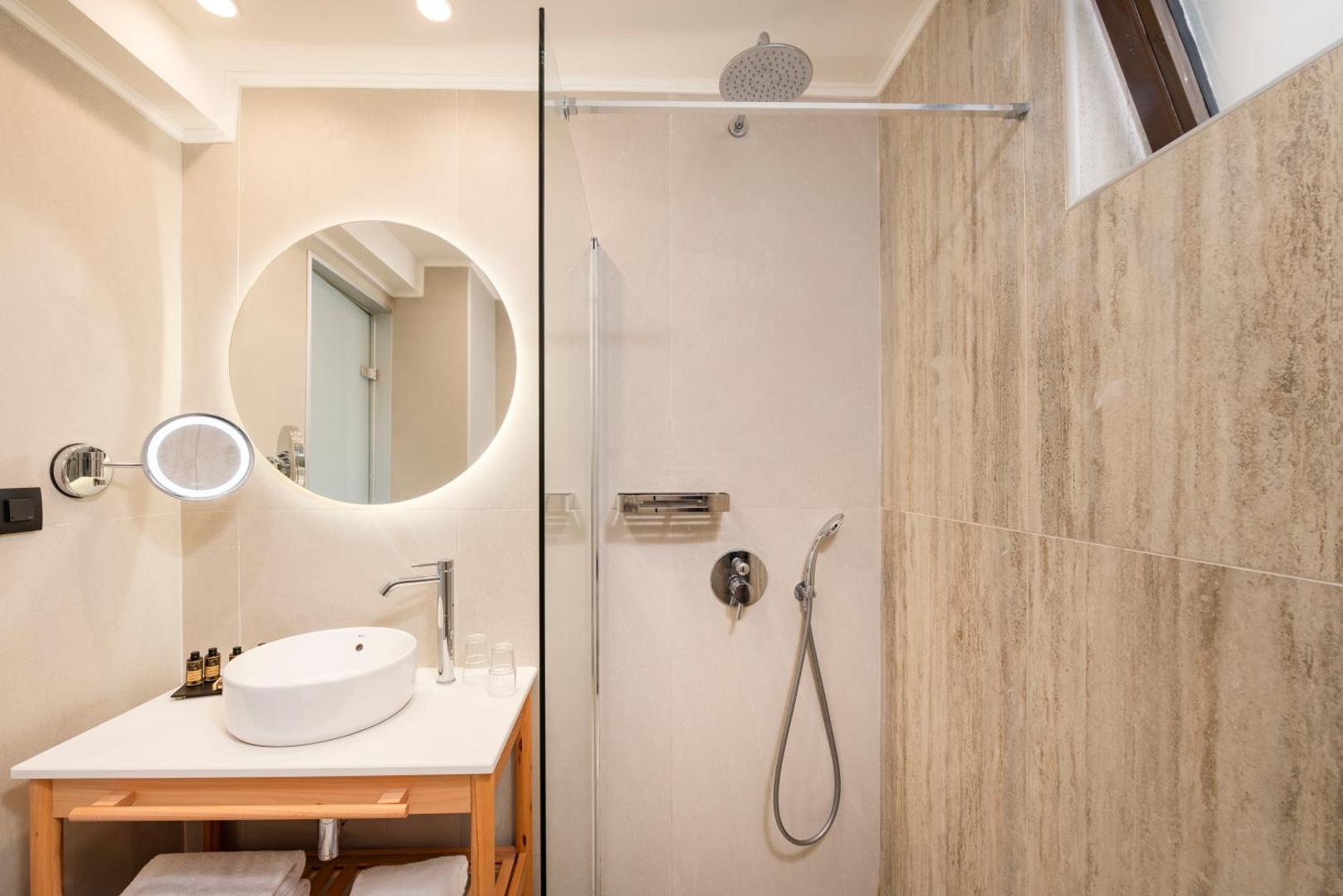 D' Andrea Mare Hotel numura vannas istaba ar modernu dušas zonu, apaļu spoguli ar apgaismojumu un dabīgā akmens apdari