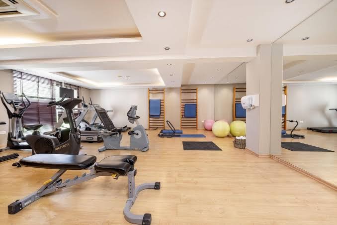 D' Andrea Mare Hotel plašais fitness centrs ar moderniem trenažieriem, skrejceļiem un vingrošanas bumbām gaišā telpā ar koka grīdu