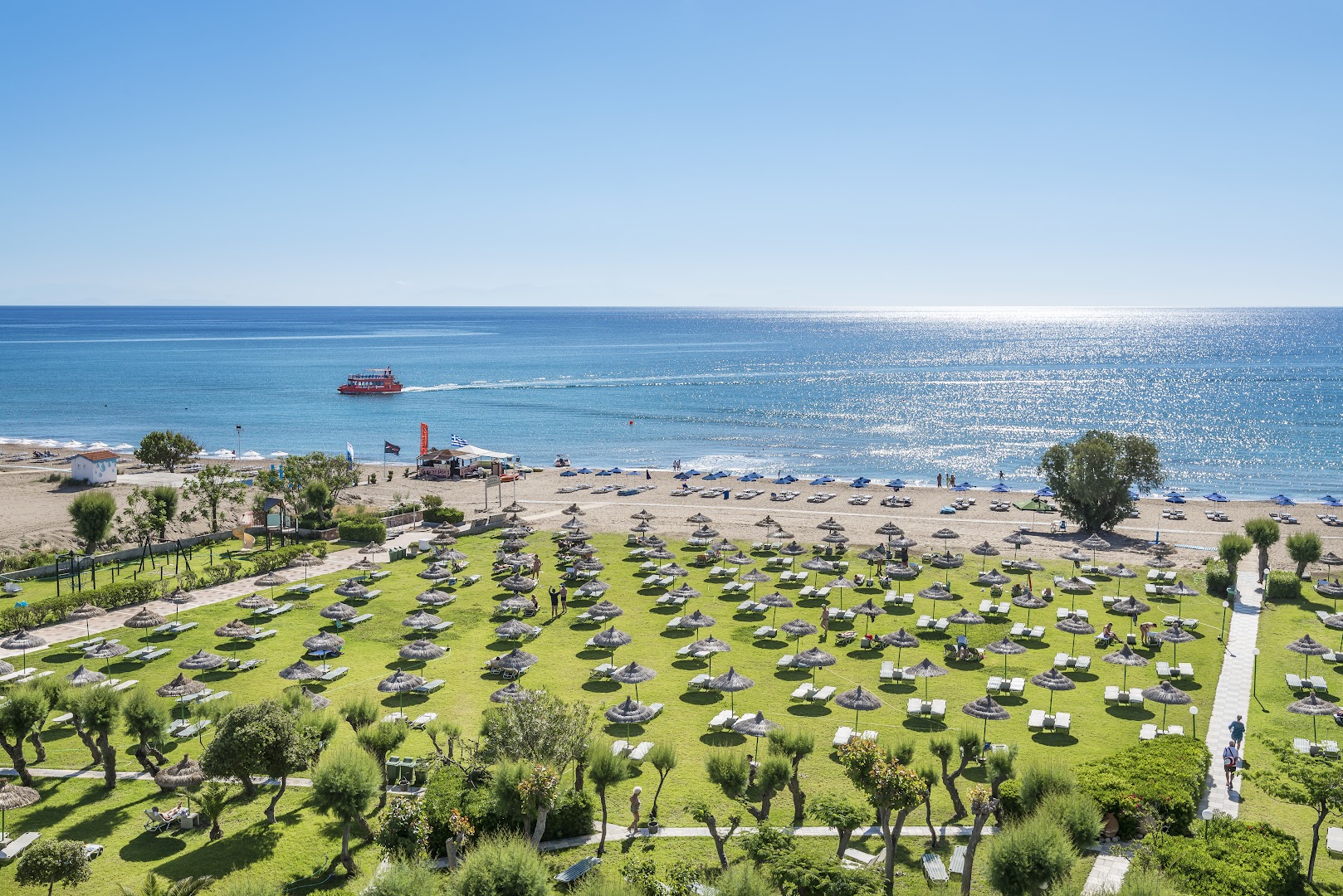 Skats no augšas uz Apollo Beach zaļo zonu ar saulessargiem un tiešu piekļuvi smilšu pludmalei Faliraki kūrortā