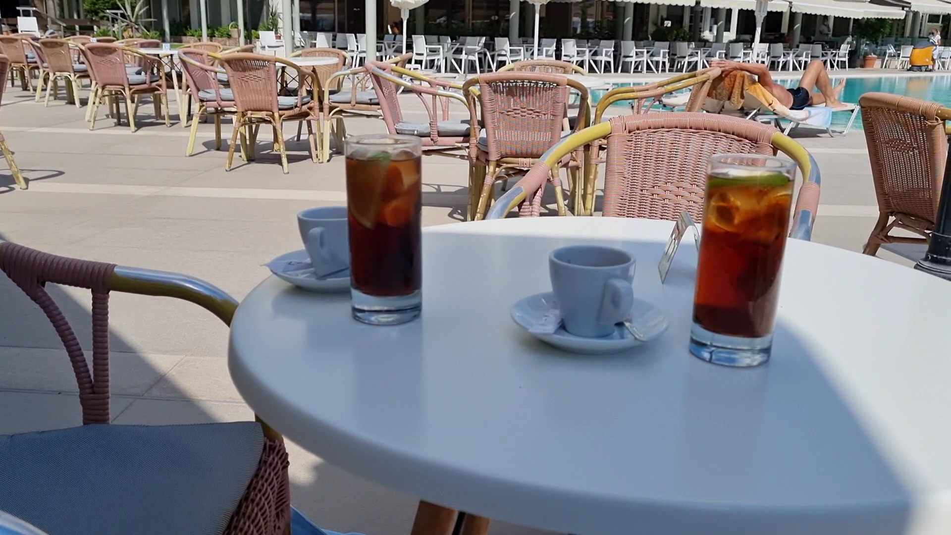 Atsvaidzinoši dzērieni un kafija uz galdiņa pie Apollo Beach baseina Rodas salā, fonā redzami atpūtas krēsli