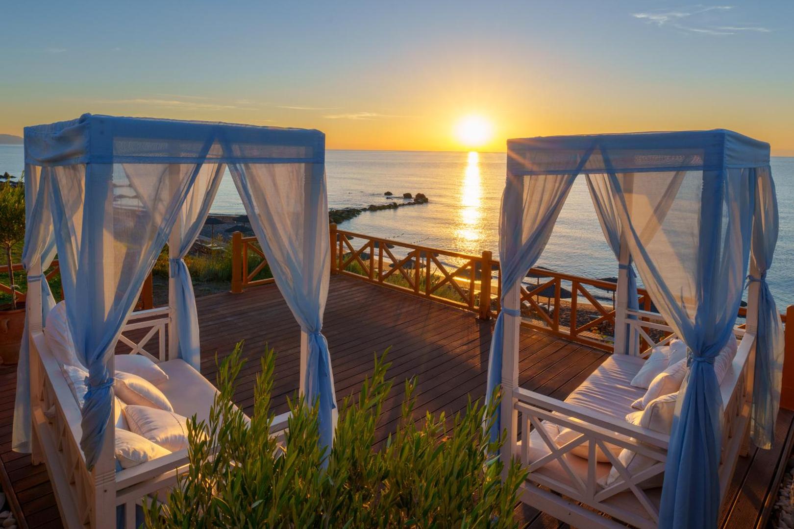 Atrium Prestige Thalasso Spa Resort koka terase ar atpūtas gultām un skatu uz jūru saulrietā Rodas dienvidos