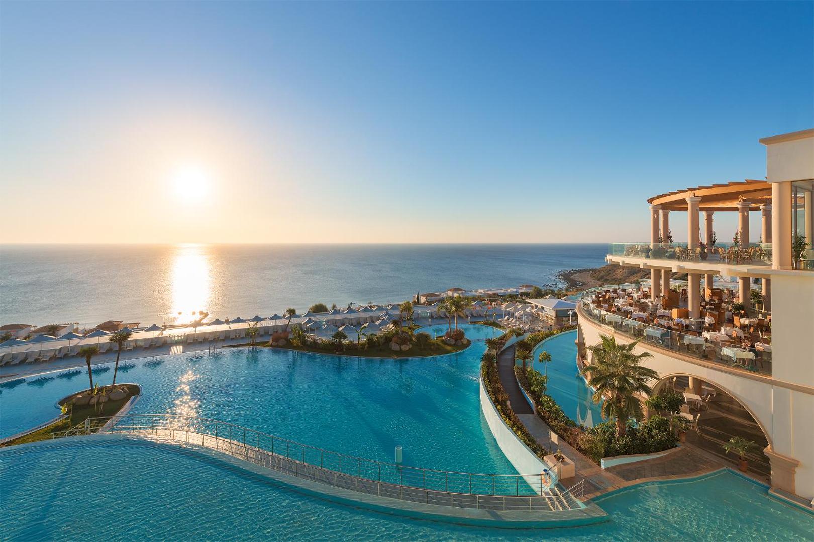 Atrium Prestige Thalasso Spa Resort & Villas skats uz baseiniem un jūru saulrietā Rodā — terases un restorāna zona