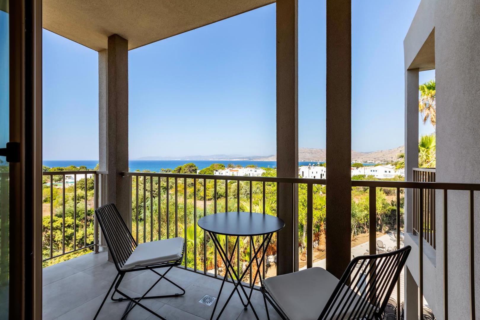 Panorāmas skats no White Olive Premium Lindos balkona uz Vidusjūru un Rodas salas piekrastes ainavu saulainā dienā