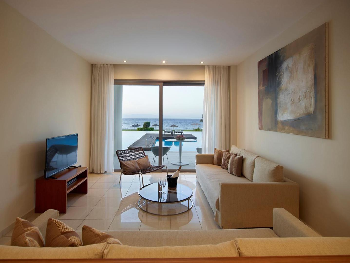 The Ixian Grand & All Suites plaša viesistabas zona luksusa numurā ar skatu uz privāto baseinu un jūras krastu