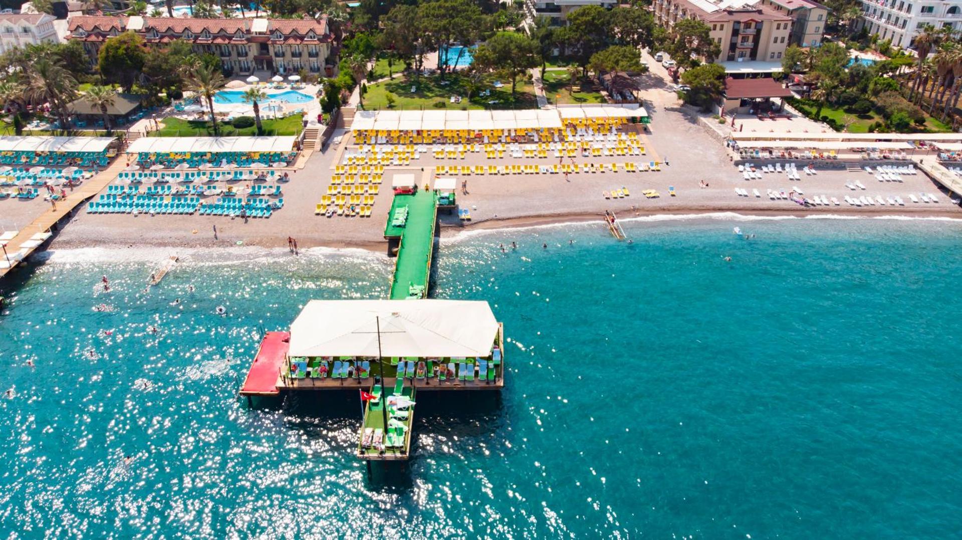 Dosinia Luxury Resort viesnīcas teritorija ar baseiniem, dārzu un pludmales piestātni — skats uz kūrorta kompleksu un jūru