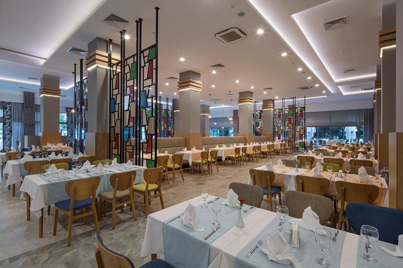 Dosinia Luxury Resort galvenais restorāns ar modernu interjeru, krāsainām stikla starpsienām un plašu galdiņu izvietojumu