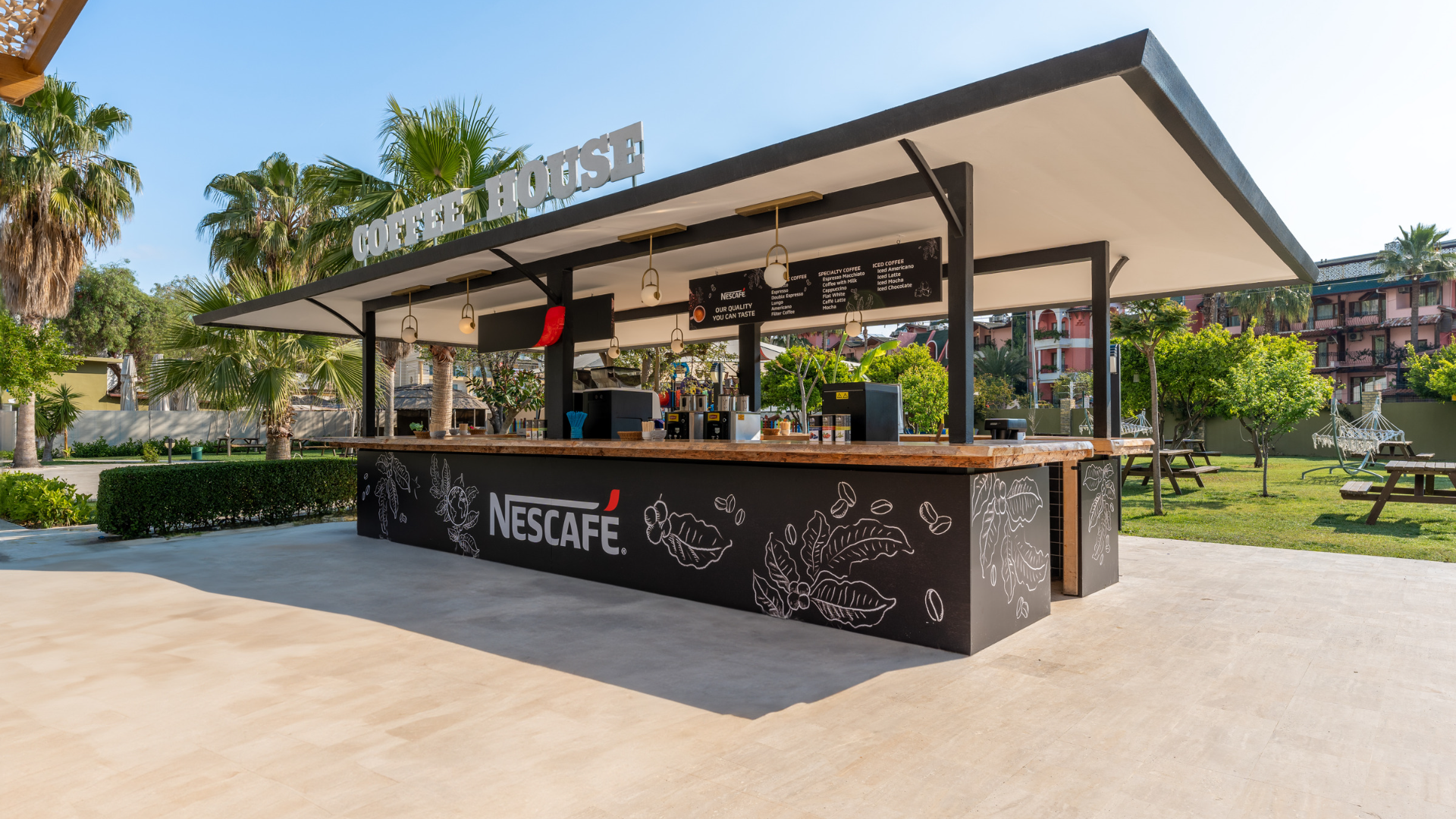Dosinia Luxury Resort āra kafijas stends Coffee House dārzā ar Nescafe zīmolu un sēdvietām zālienā