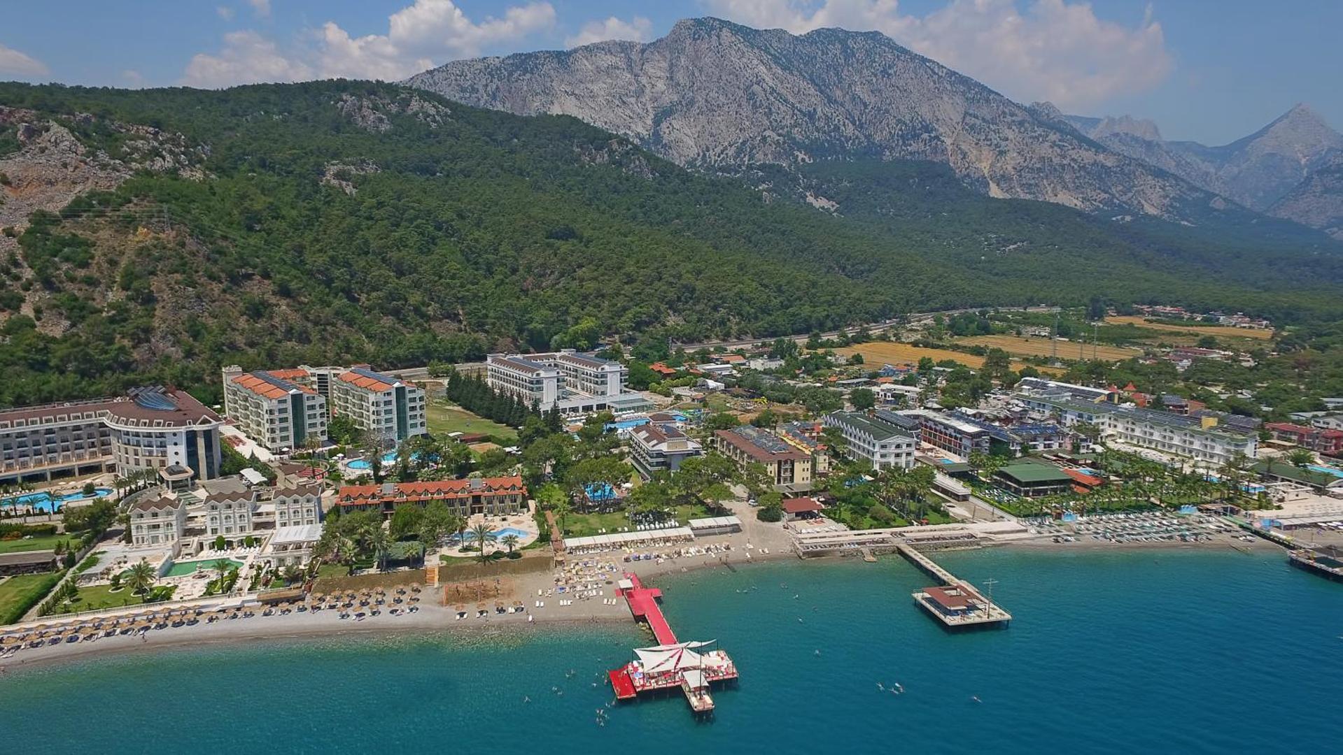 Dosinia Luxury Resort panorāmas skats no putna lidojuma uz pludmali, piestātni un viesnīcas kompleksu pie Vidusjūras