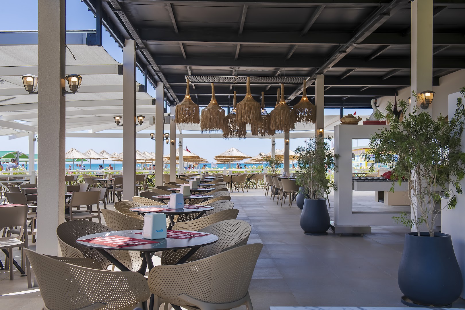 Belek Beach Resort pludmales bārs un restorāns ar skatu uz jūru un salmu saulessargiem fonā