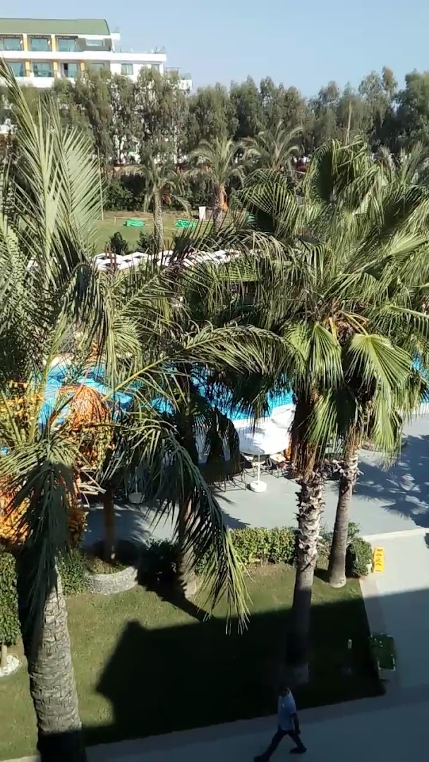 Belek Beach Resort skats no augšas uz palmu dārzu un zilo baseinu Turcijas piekrastē saulainā dienā