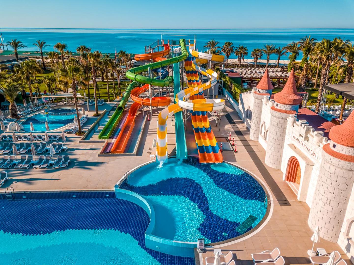 Belek Beach Resort akvaparks ar krāsainiem slidkalniņiem un bērnu pili pie zilā baseina un Vidusjūras krasta