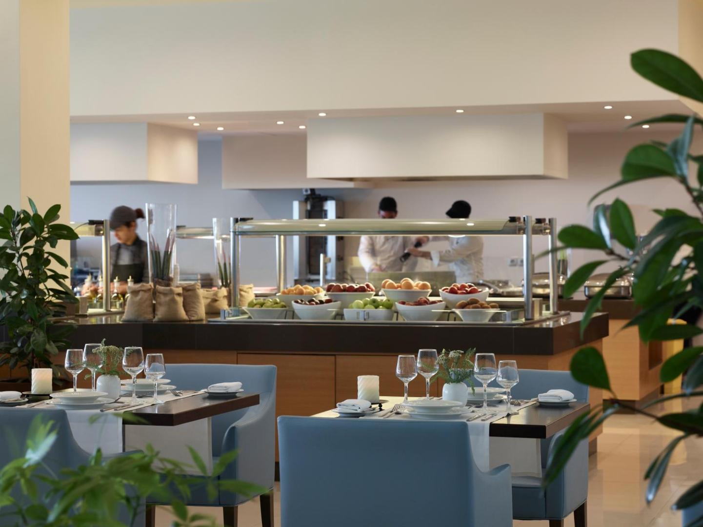 Apollo Blue Hotel galvenais restorāns Rodas salā ar bufetes tipa galdiem, svaigiem augļiem un pavāriem, kas gatavo ēdienu viesu priekšā.