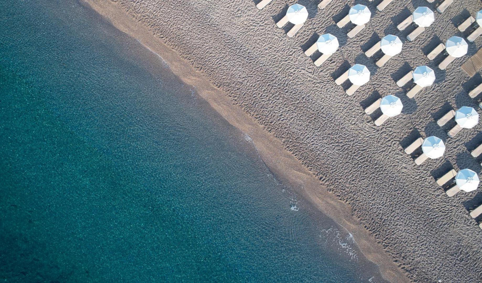Princess Andriana Resort & Spa privātā pludmale Rodā no putna lidojuma — dzidrs ūdens un sakoptas atpūtas vietas ar saulessargiem