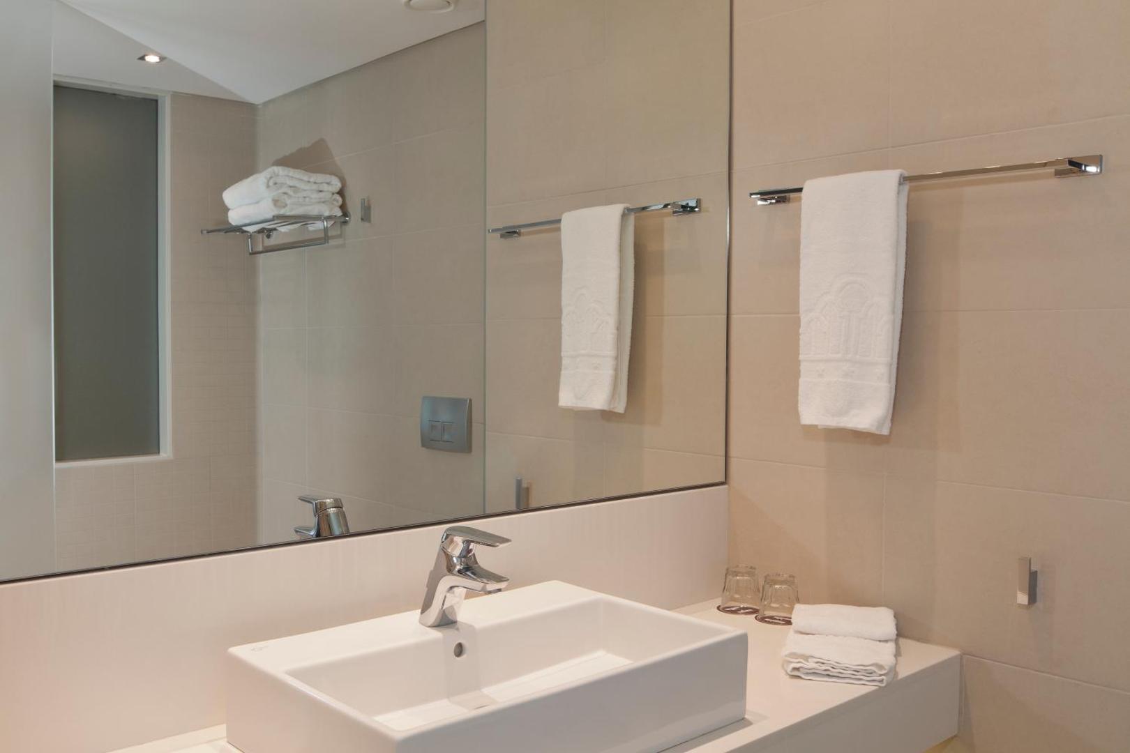 Gaišs Princess Andriana Resort & Spa viesnīcas numura vannasistabas interjers ar modernu izlietni un lielu spoguli