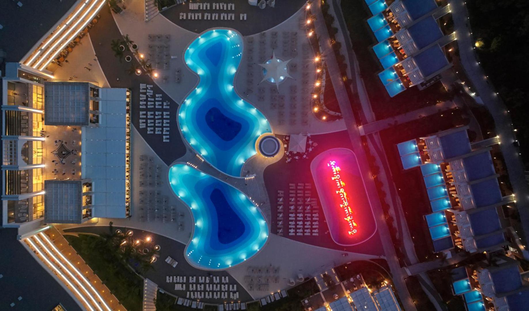 Princess Andriana Resort & Spa vakara apgaismojums pie baseiniem Rodā — izgaismotas terases, strūklakas un moderna kūrorta arhitektūra naktī