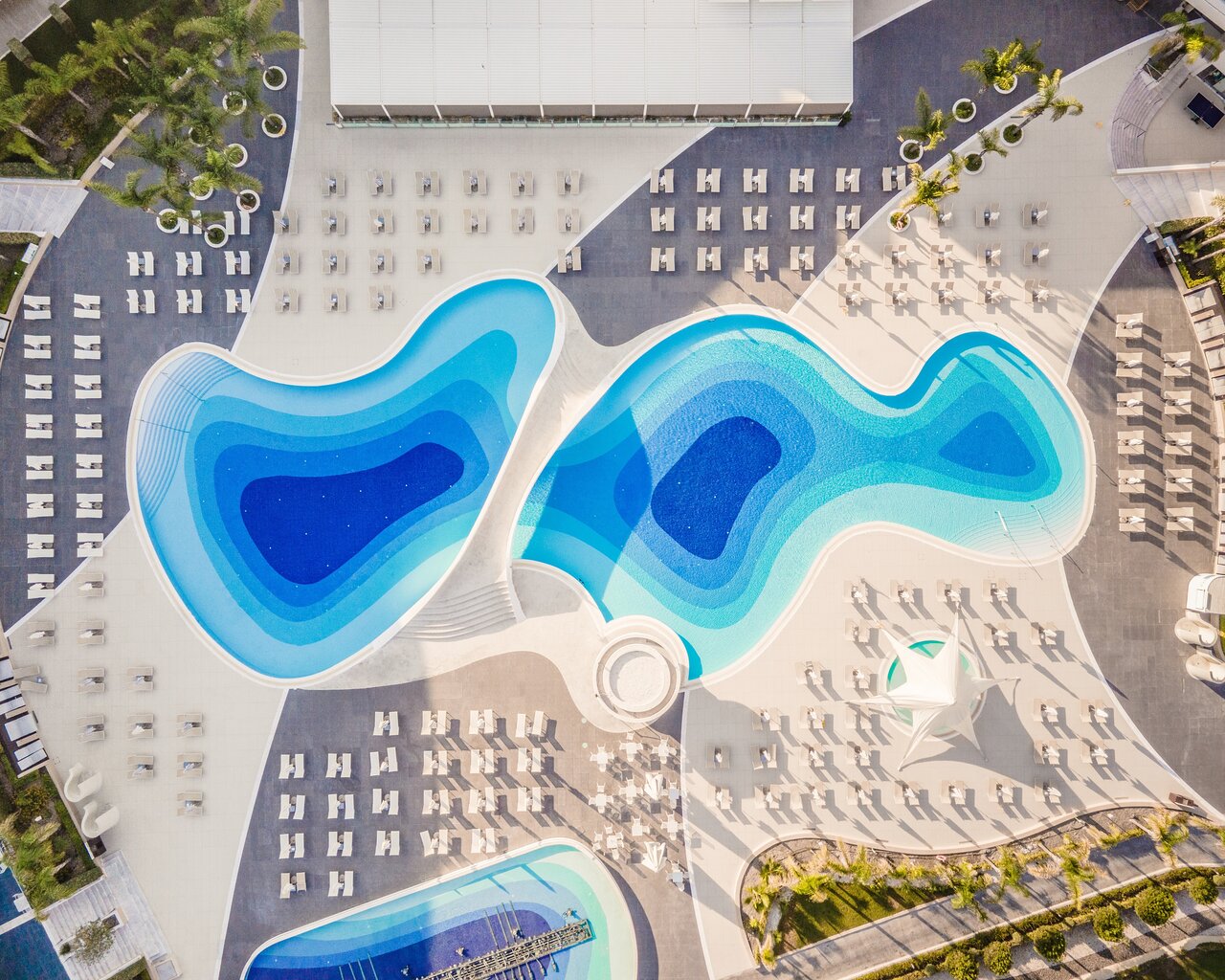 Princess Andriana Resort & Spa galvenā baseina skats no augšas Rodas salā — unikāls dizains ar ziliem toņiem un sauļošanās krēsliem