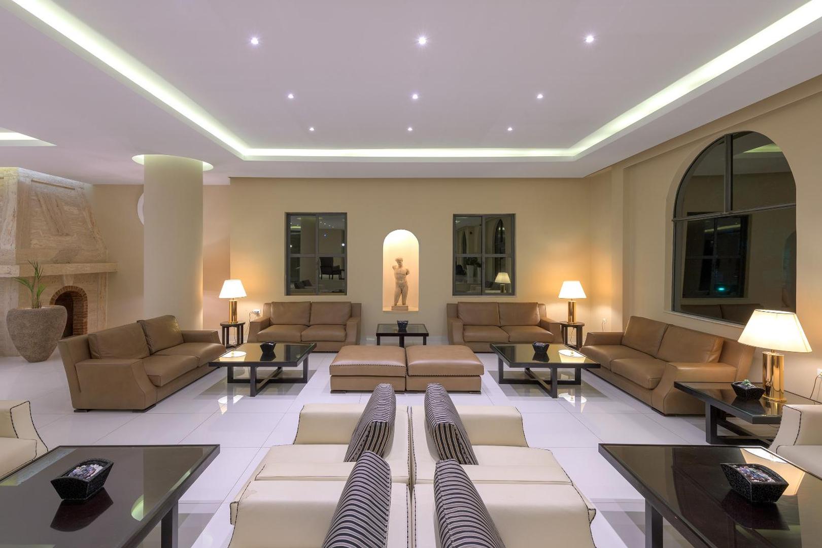 Lindos Village Resort & Spa lobby atpūtas zona ar ādas dīvāniem, kamīnu un klasisku interjeru Rodas salas kūrortā