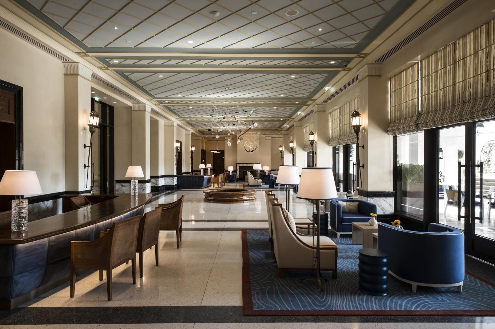 Regent Porto Montenegro viesnīcas plašais vestibils ar elegantiem atpūtas krēsliem, marmora grīdu un greznu interjeru Melnkalnes piekrastē