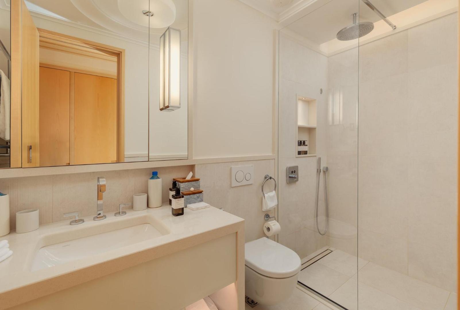 Regent Porto Montenegro numura vannas istaba gaišos toņos ar plašu dušas zonu, lielu spoguli un modernu dizainu