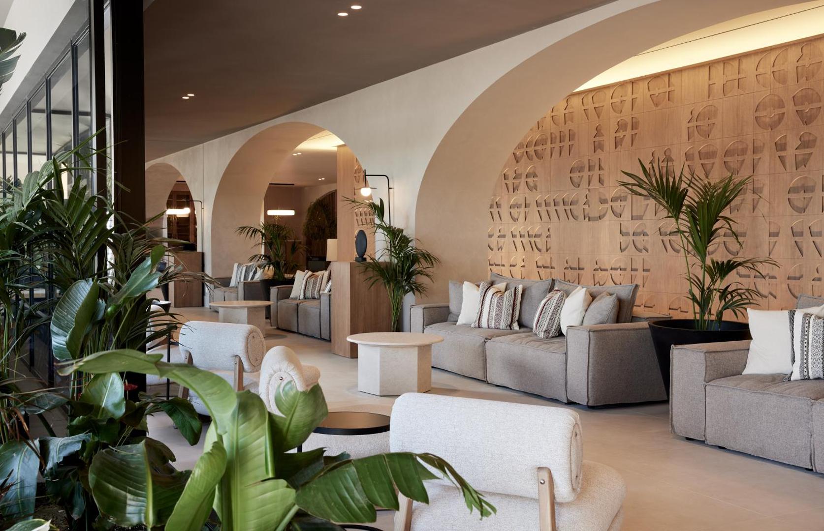Elissa Lifestyle Resort lobby atpūtas zona ar pelēkiem dīvāniem, dizaina arkām un telpaugiem, radot modernu un mājīgu atmosfēru
