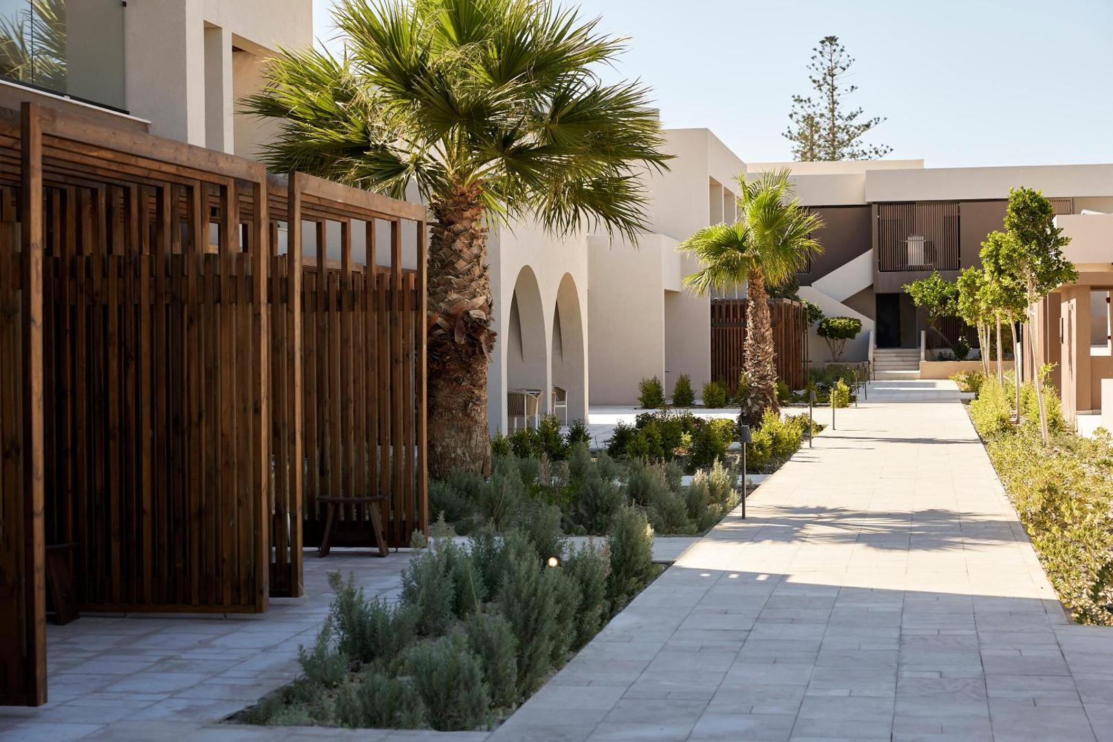 Elissa Lifestyle Resort labiekārtotā teritorija ar flīzētiem celiņiem, palmām un koka dekoratīvajiem elementiem starp viesnīcas korpusiem Rodā