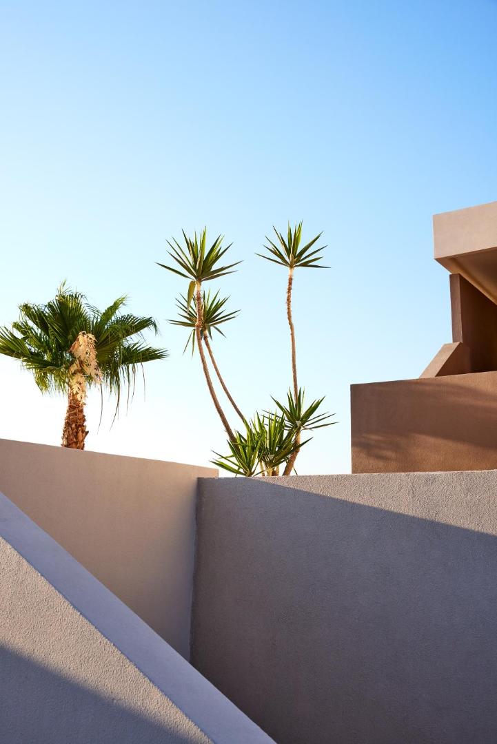 Elissa Lifestyle Resort arhitektūras detaļas ar palmām un jukas kokiem uz zilu debesu fona Rodas salā — moderna un saulaina vide