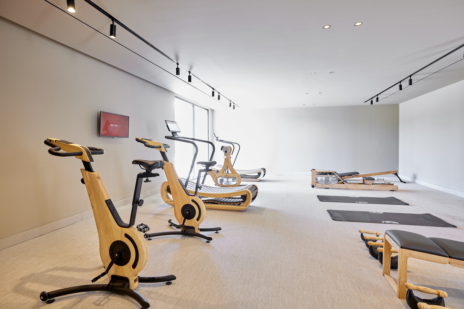 Elissa Lifestyle Resort modernā fitness zāle ar koka apdares trenažieriem, velotrenažieriem un jogas paklājiņiem gaišā un plašā telpā