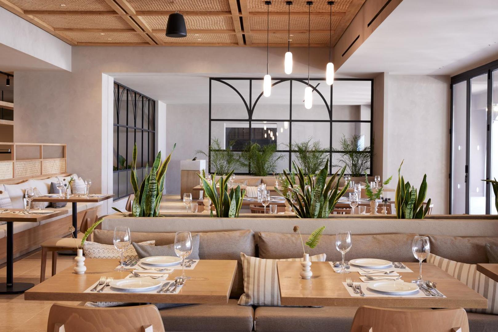 Elissa Lifestyle Resort iekštelpu restorāns ar modernu dizainu, koka griestiem, zaļajiem augiem un elegantiem galdiem Rodas salā