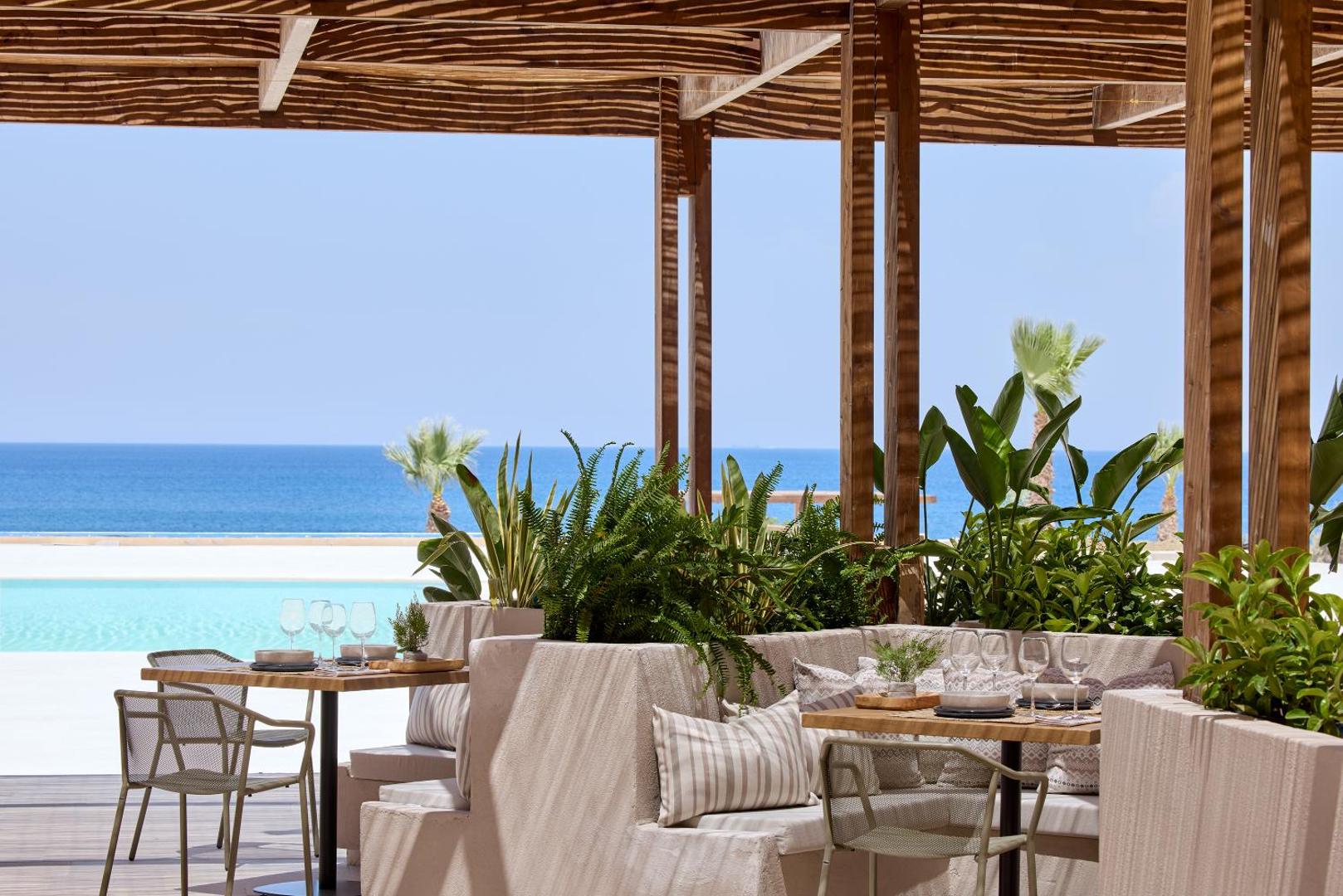 Elissa Lifestyle Resort restorāna terase Rodas salā ar skatu uz jūru un baseinu, koka nojume un eleganti klāti galdi