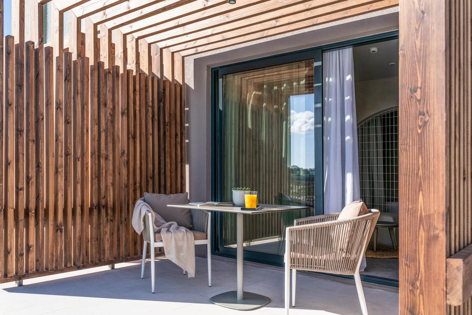 Elissa Lifestyle Resort privātā terase ar koka apdari un atpūtas krēsliem Rodā — vieta brokastīm vai atpūtai