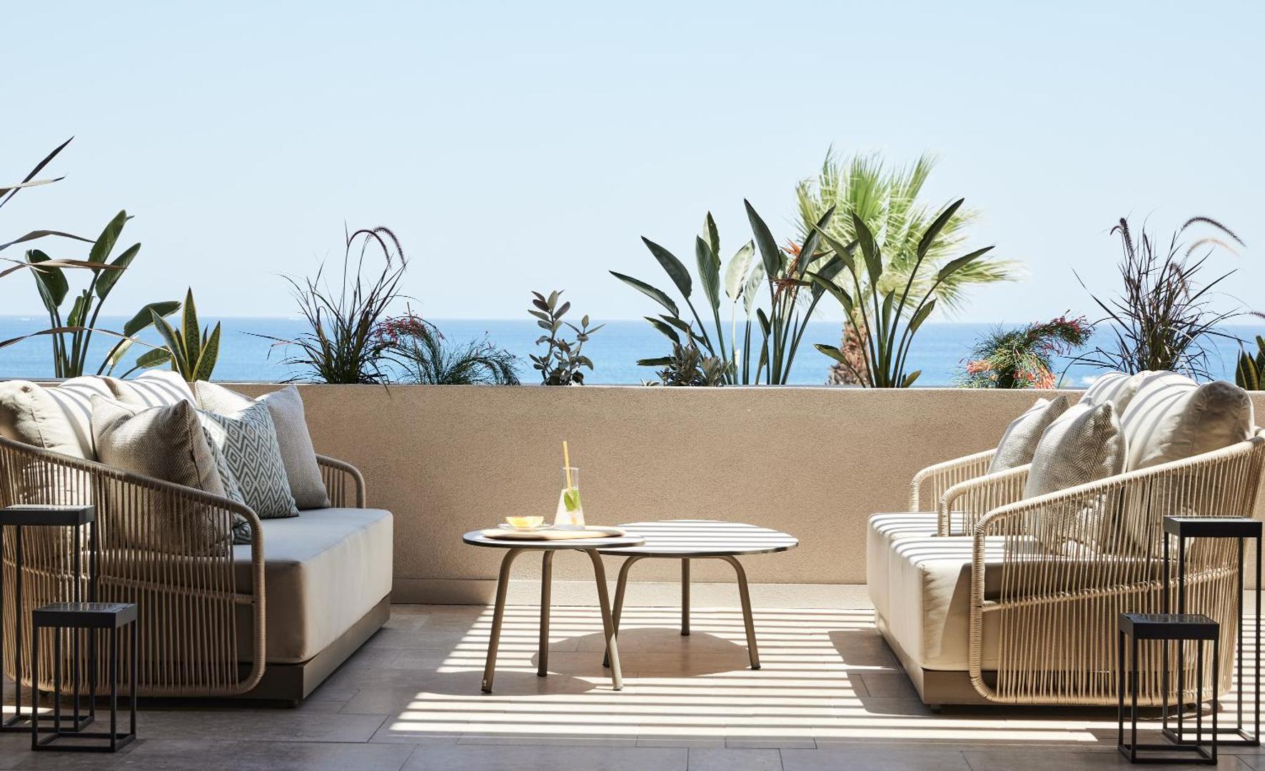 Elissa Lifestyle Resort numura terase ar modernām mēbelēm, dīvāniem un skatu uz Vidusjūru Rodas piekrastē, ko ieskauj palmas