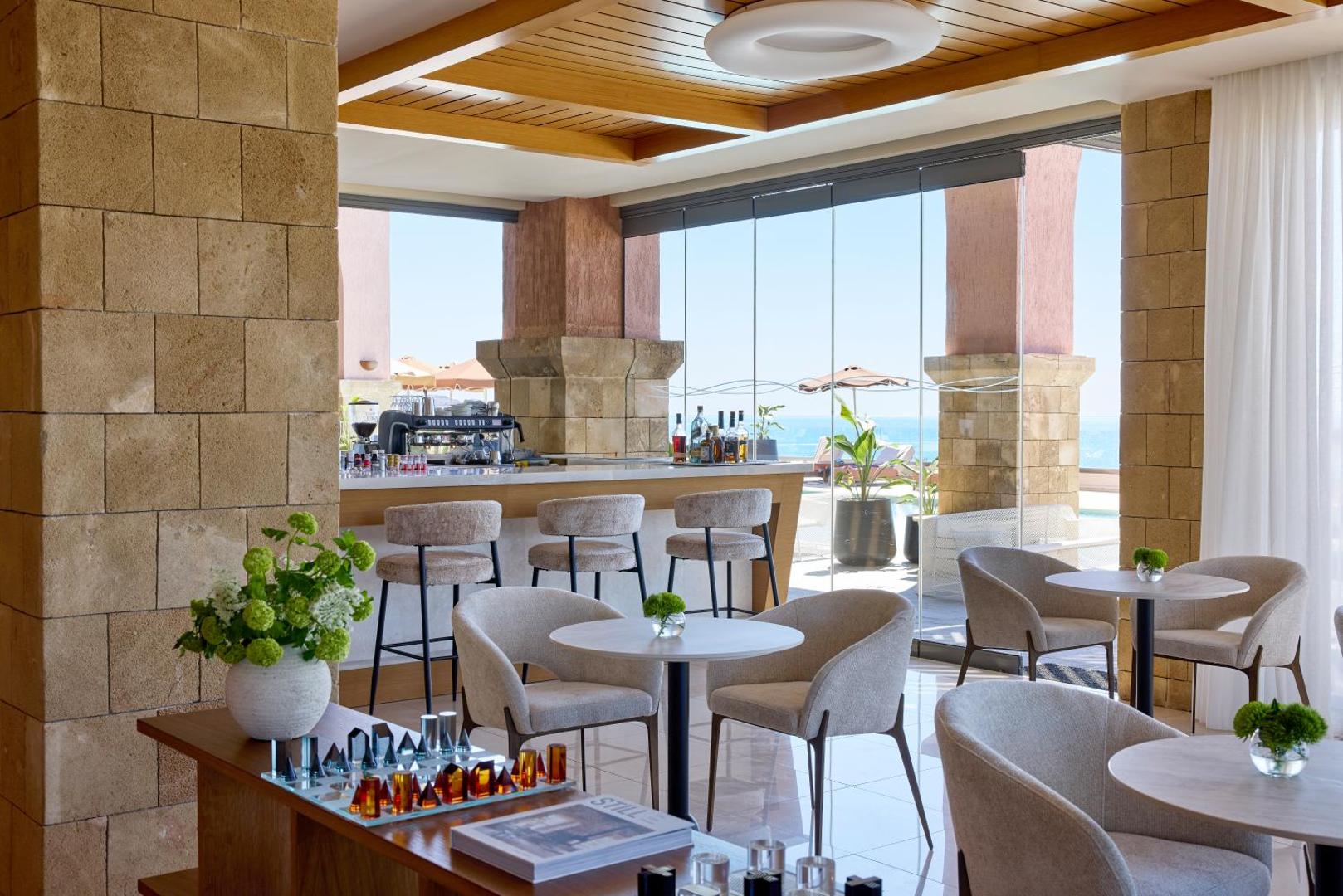Boutique 5 Hotel & Spa bārs ar skatu uz jūru Rodā — gaišs interjers, akmens kolonnas un āra terase