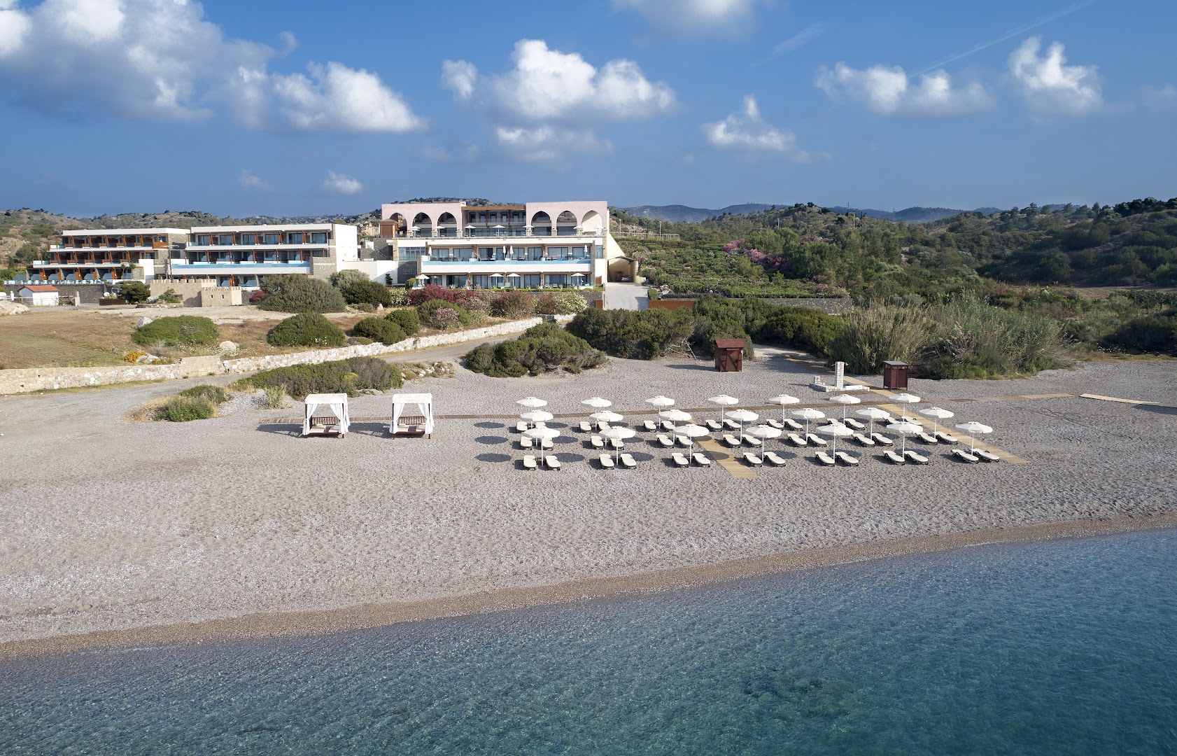 Boutique 5 Hotel & Spa privātā oļu pludmale ar saulessargiem, zviļņiem un gultām pie dzidri zilā jūras ūdens Rodā