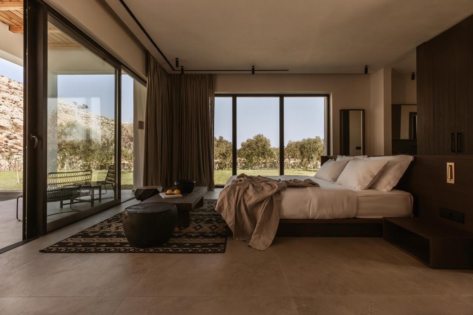 Casa Cook Rhodes viesnīcas numurs ar plašiem panorāmas logiem, terasi un skatu uz dārzu Rodas salā, Grieķijā — minimālistisks dizains