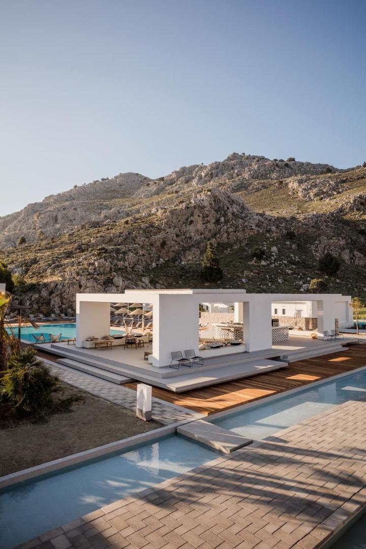 Casa Cook Rhodes modernā atpūtas terase un dekoratīvie baseini Rodas salā — skats uz kalniem saulrietā