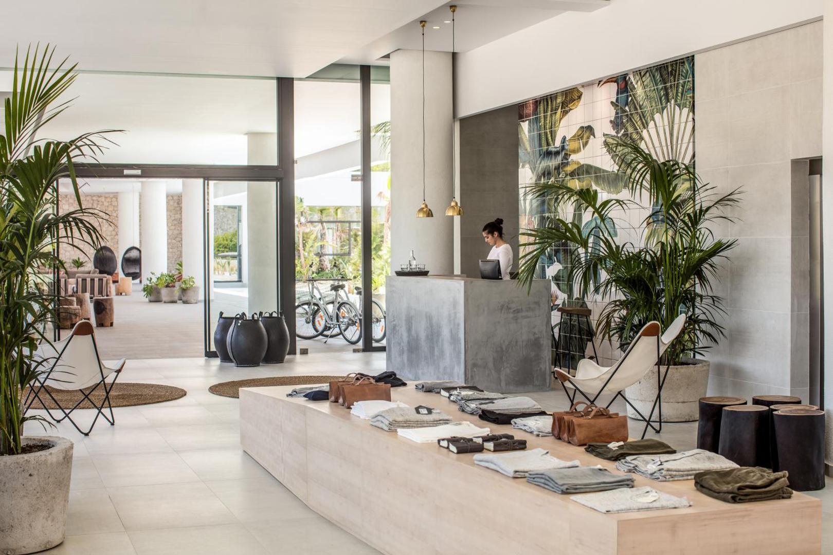 Casa Cook Rhodes viesnīcas vestibils ar modernu betona recepcijas galdu, dizaina mēbelēm un nelielu boutique stila veikalu Rodas salā