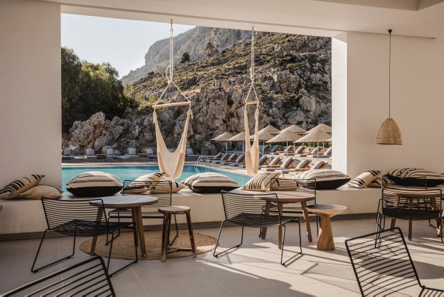 Casa Cook Rhodes atpūtas zona pie baseina ar šūpuļtīkliem, dizaina krēsliem un skatu uz Rodas salas klintīm