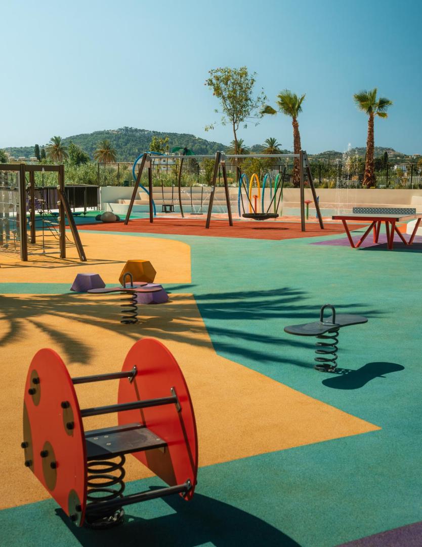 Mitsis Faliraki Beach Hotel & Spa plašs bērnu rotaļu laukums ar šūpolēm un slidkalniņiem uz krāsaina, droša seguma Rodas salā