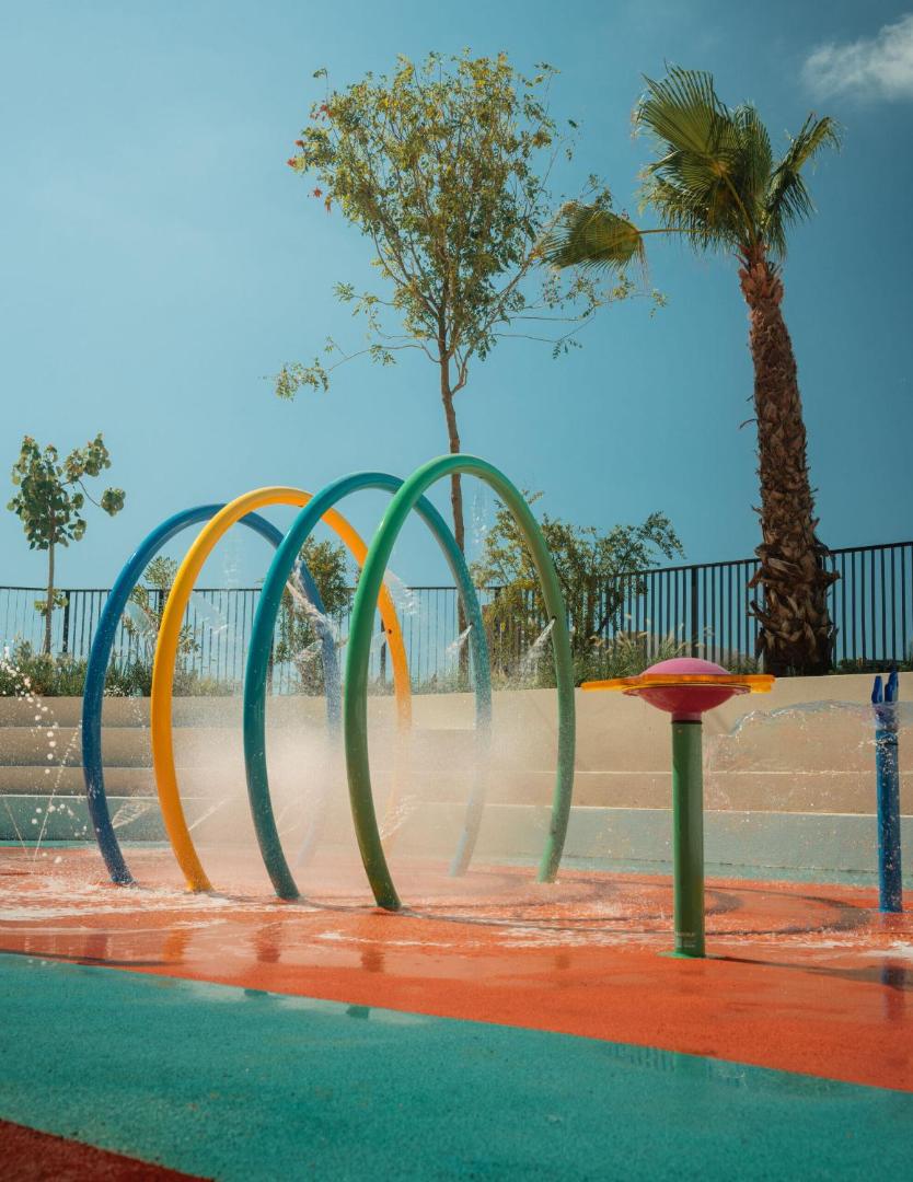 Mitsis Faliraki Beach Hotel & Spa bērnu ūdens atrakciju zona ar krāsainām arkām un strūklakām piekrastes kūrortā Rodā