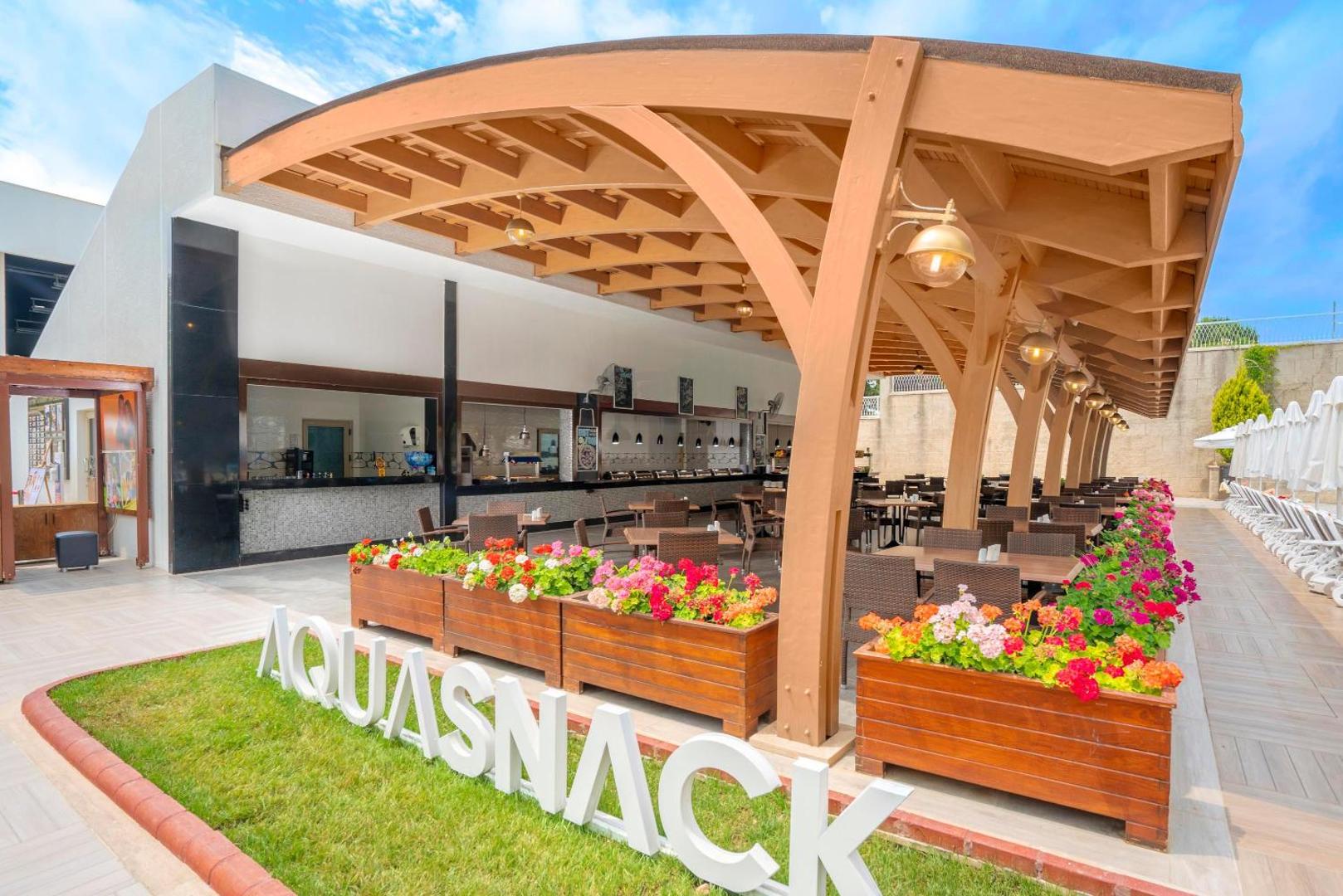 Kirman Sidemarin Beach & Spa uzkodu bārs Aqua Snack ar koka nojumi, ziedu kastēm un galdiņiem āra zonā
