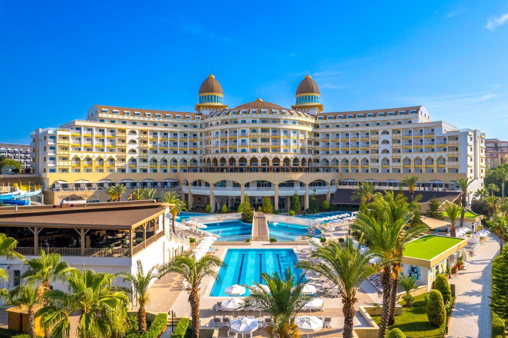 Kirman Sidemarin Beach & Spa viesnīcas galvenā ēka un āra baseinu komplekss Sidē, Turcijā — plaša teritorija ar palmām un sauļošanās krēsliem